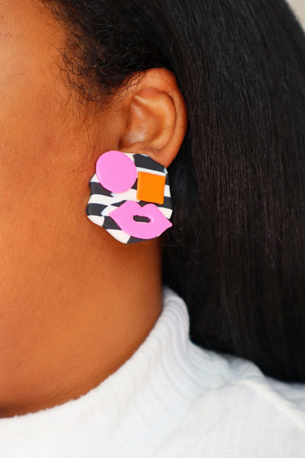 Boucles d’oreilles avant-gardistes en argile polymère avec visages abstraits : fond à carreaux noir et blanc avec détails roses et orange vifs - Clous uniques en argile polymère